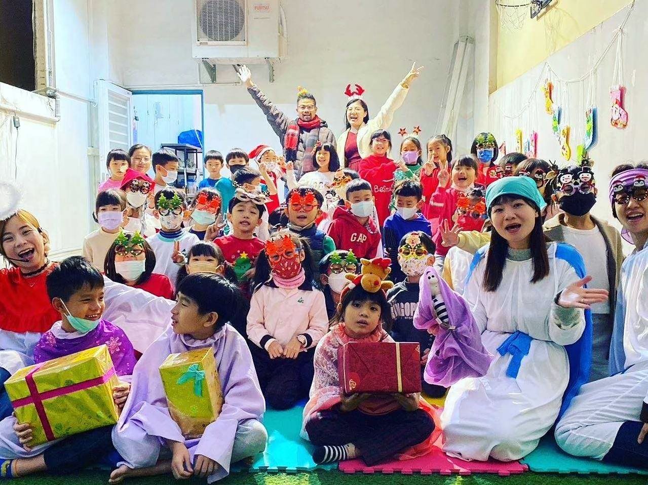 孩子們穿著節慶盛裝,老師們手捧禮物在室內合照。現場裝飾喜氣洋洋。