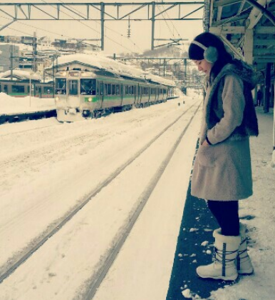雪中的火車站裡,有人正在等火車。背景是建築物。