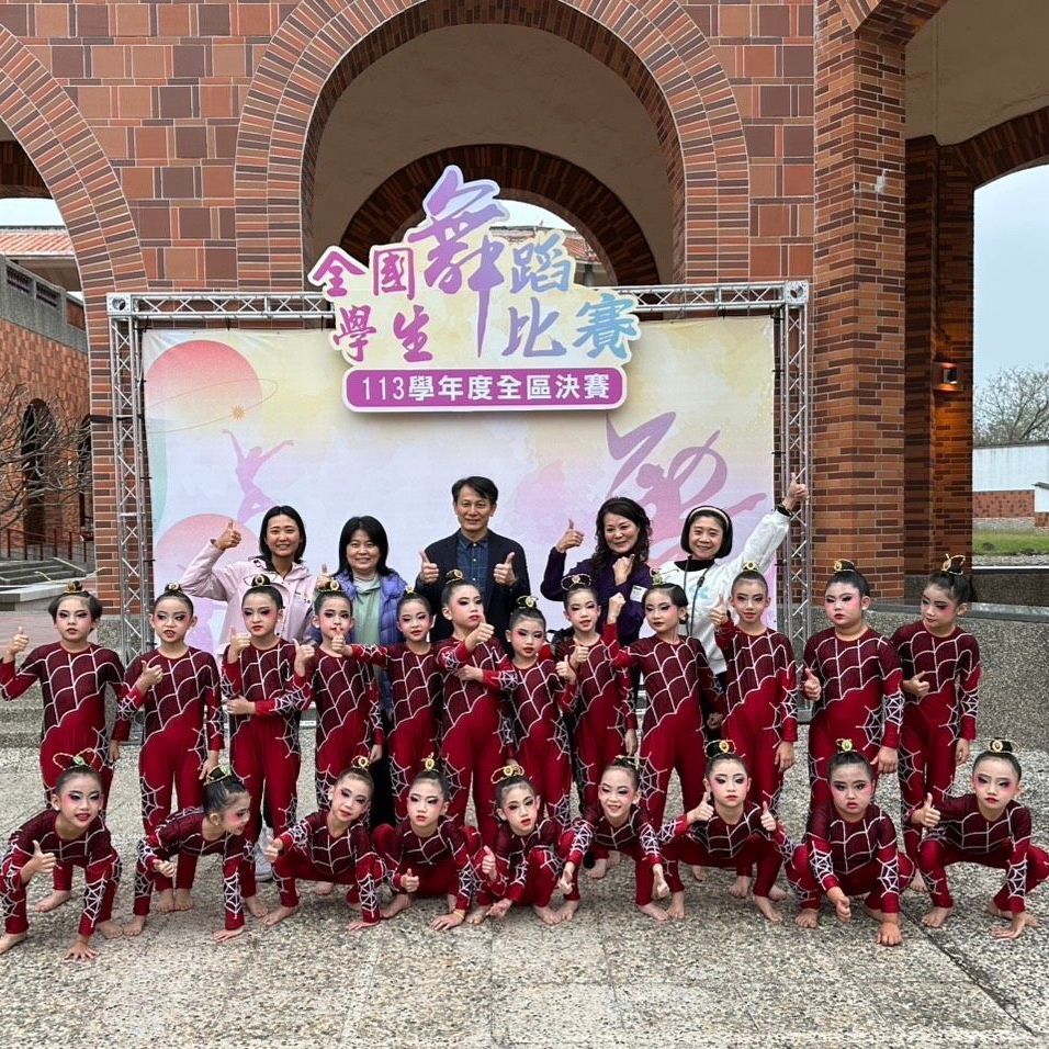 一群身穿栗色服裝的舞者和教練在橫幅前擺姿勢拍照。