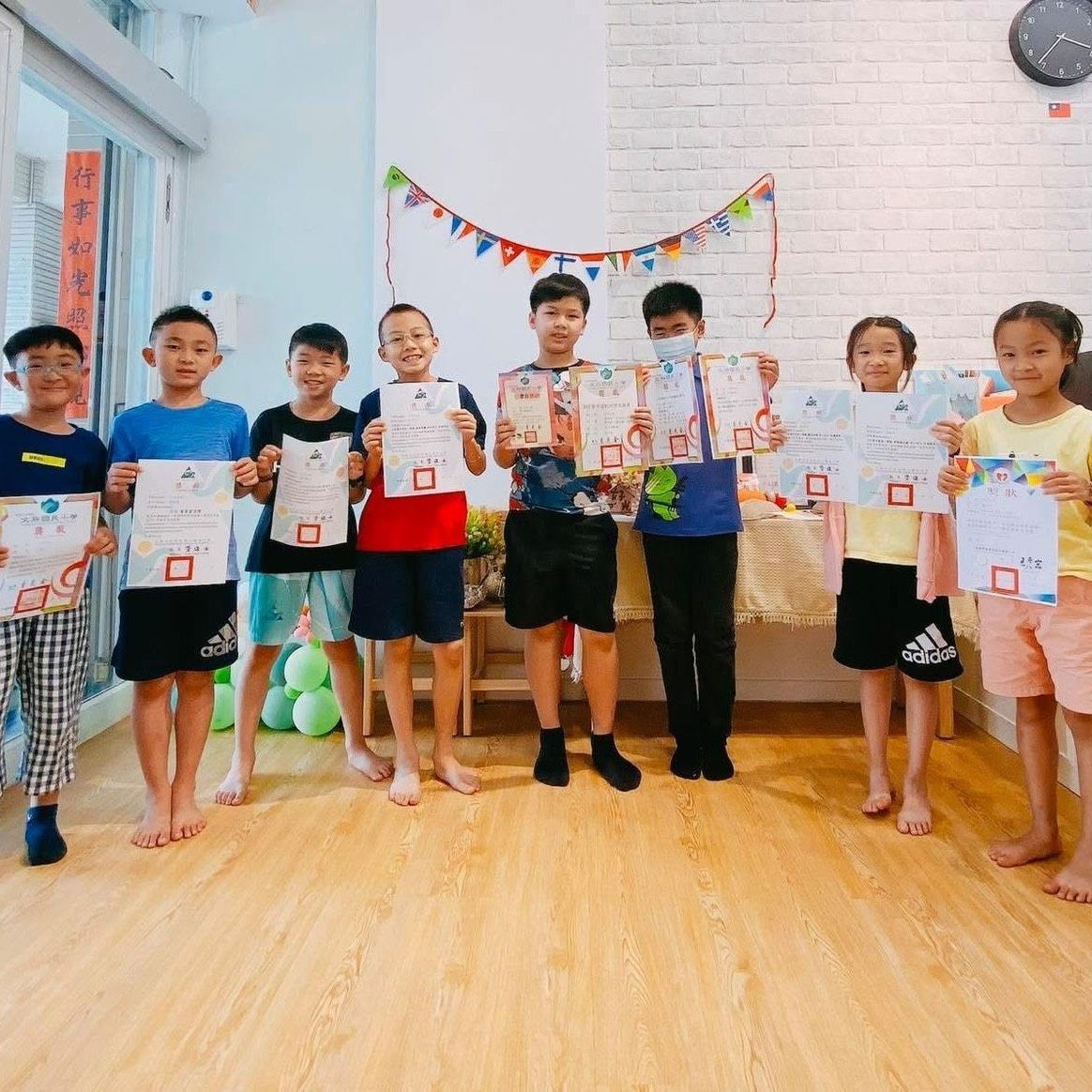 孩子們手持證書，在裝飾一新的房間裡合影留念。