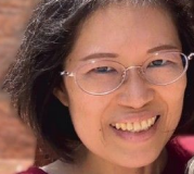 戴眼鏡的女子,笑容燦爛,露出牙齒。