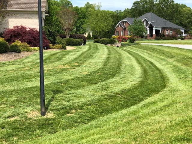 A lush green lawn is being mowed in front of a house.