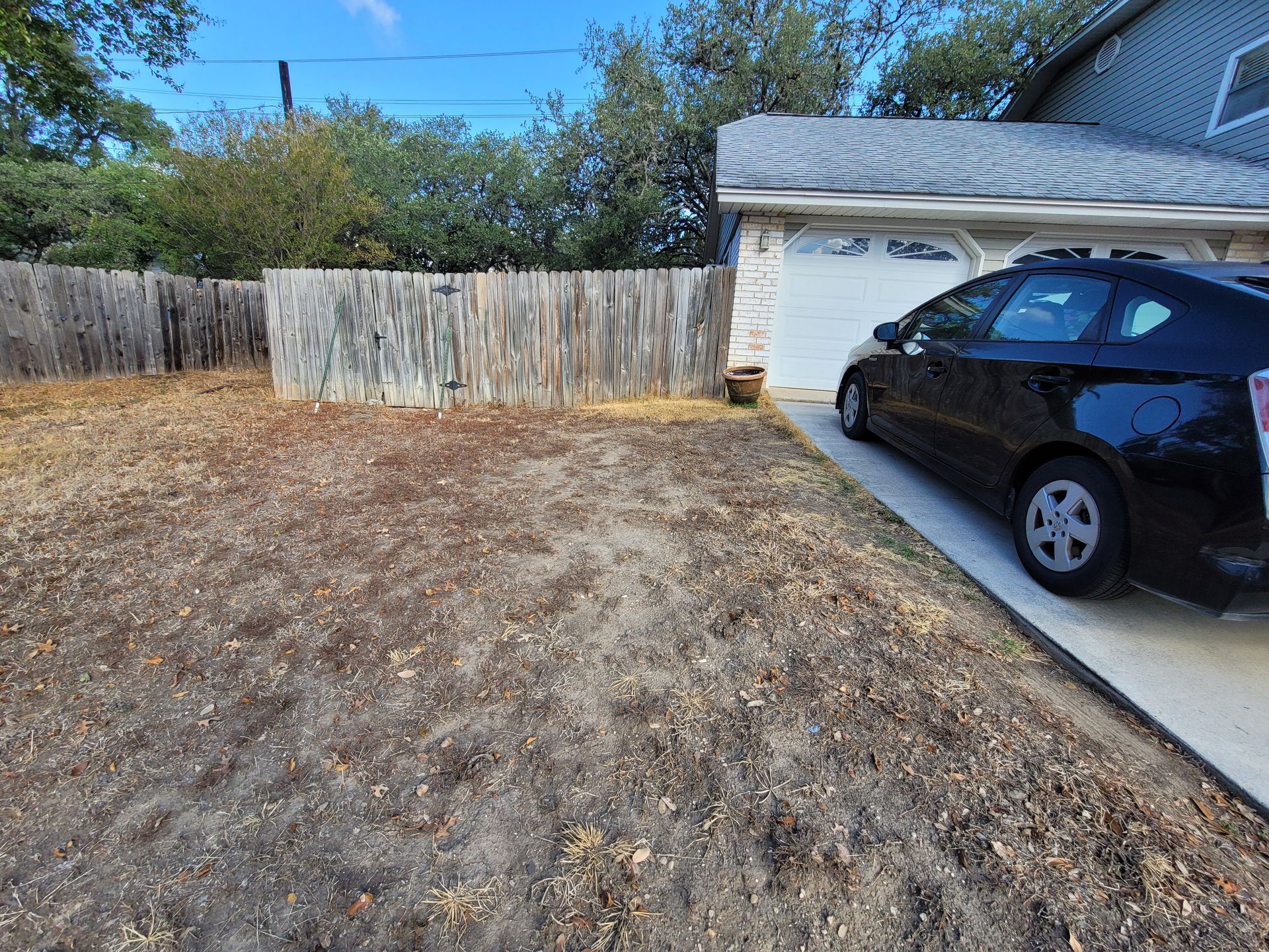 A black car is parked in a driveway in front of a house .