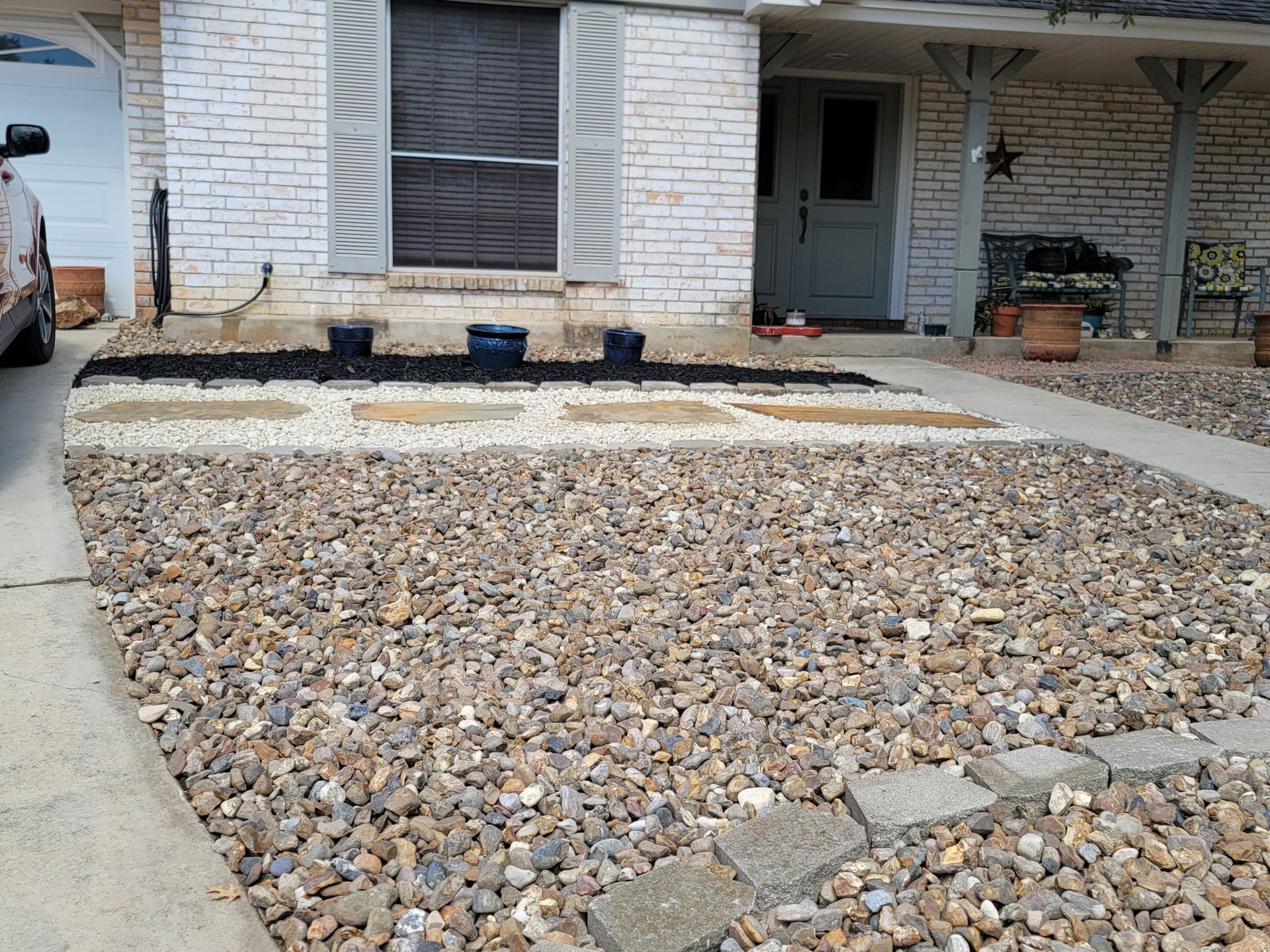 A car is parked in front of a white brick house