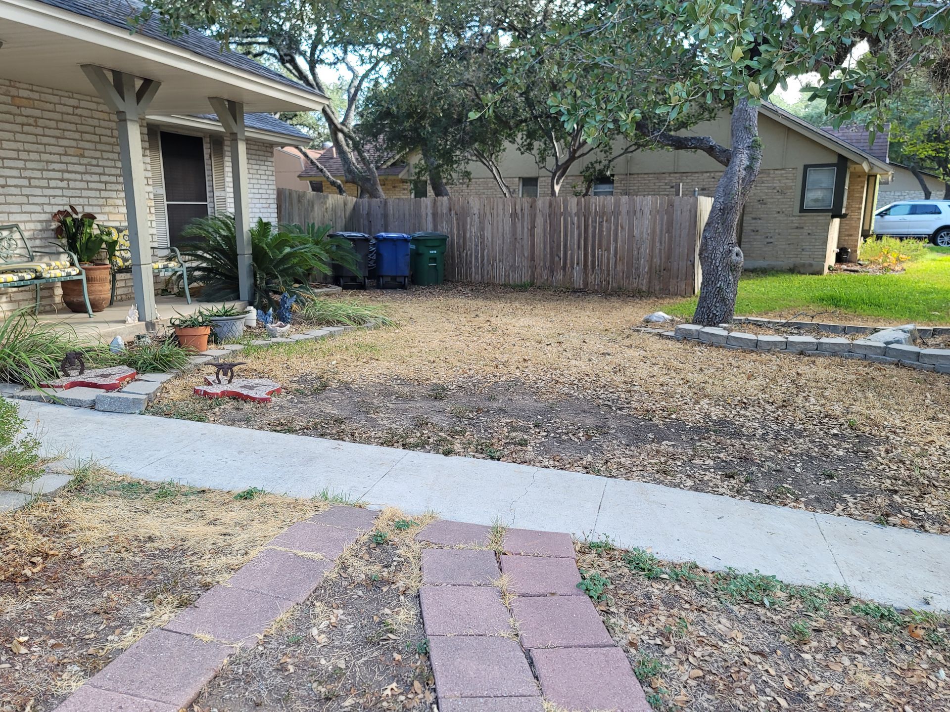 A brick walkway leading to a house with a fence in the background .