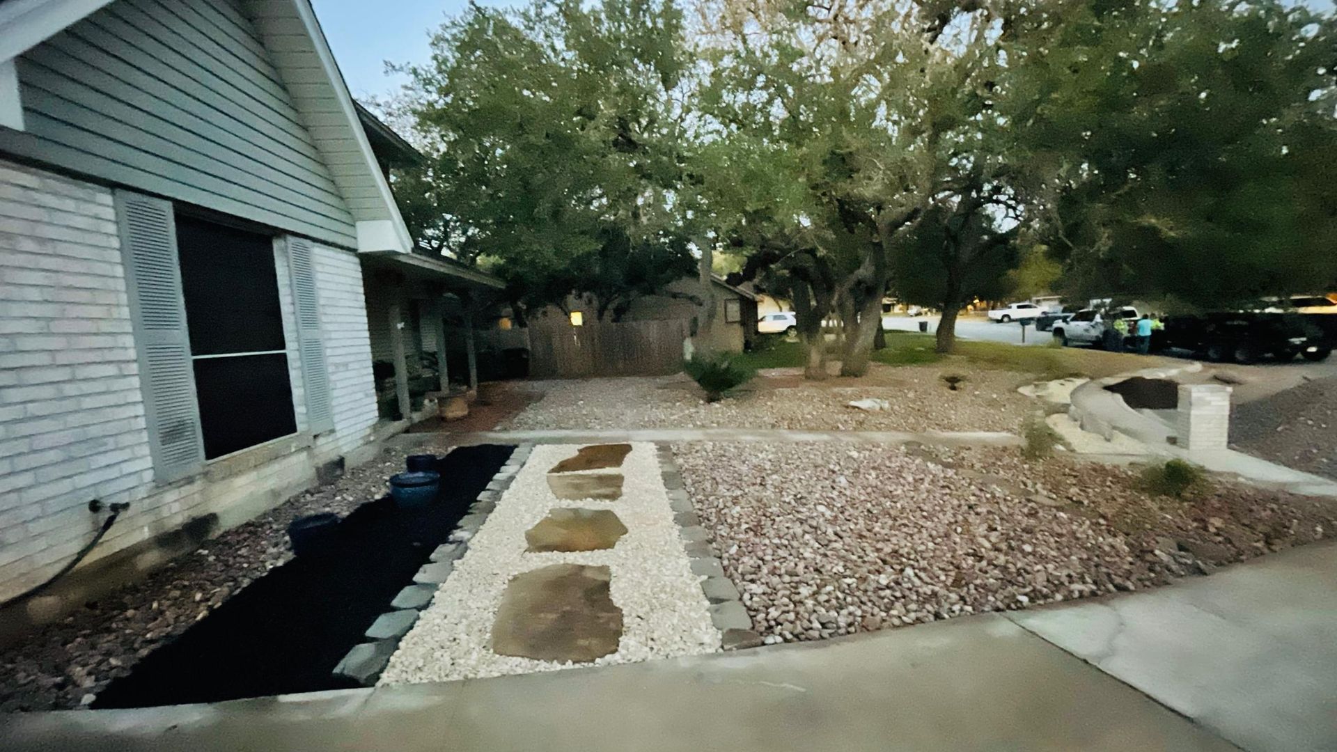 A white brick house with a gravel driveway in front of it .