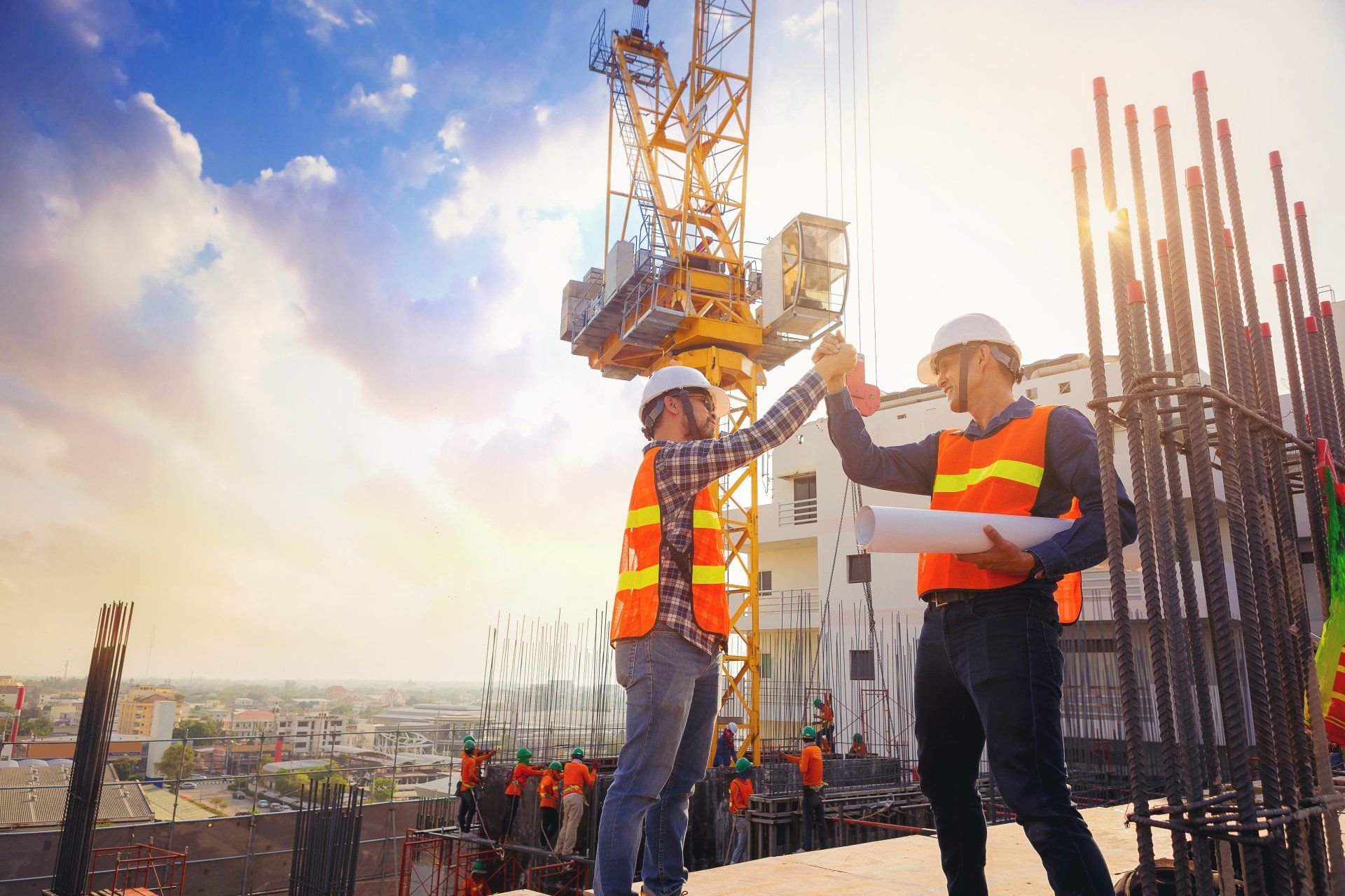Two construction workers are giving each other a high five at a construction site.
