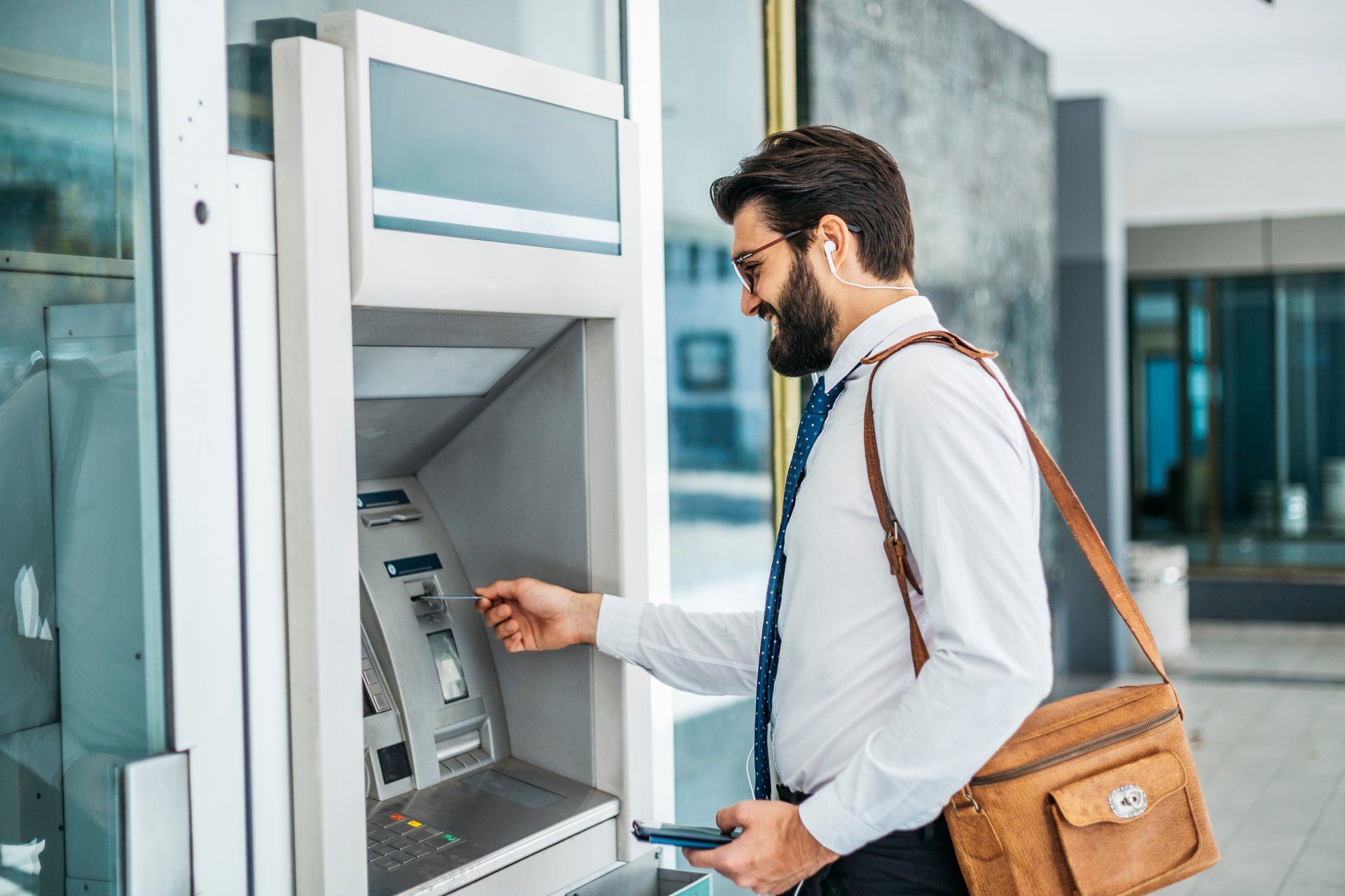 A man is using an atm machine to withdraw money.