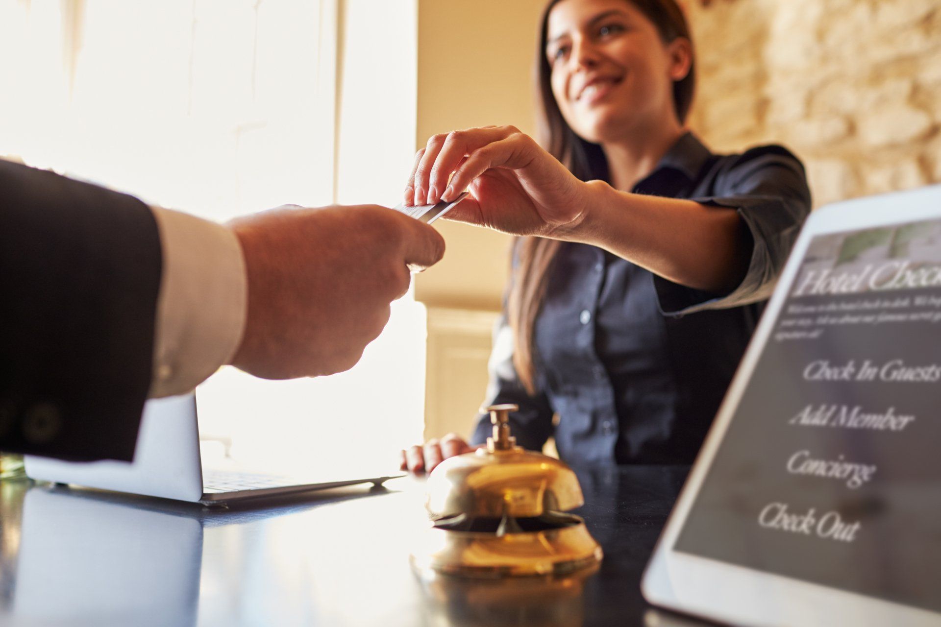 A woman is giving a credit card to a man at a hotel counter.
