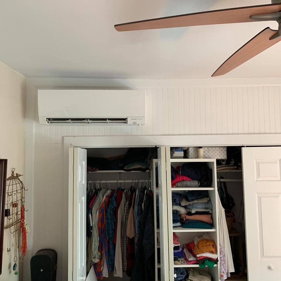 White air conditioner unit mounted above a closet, ceiling fan in the background.