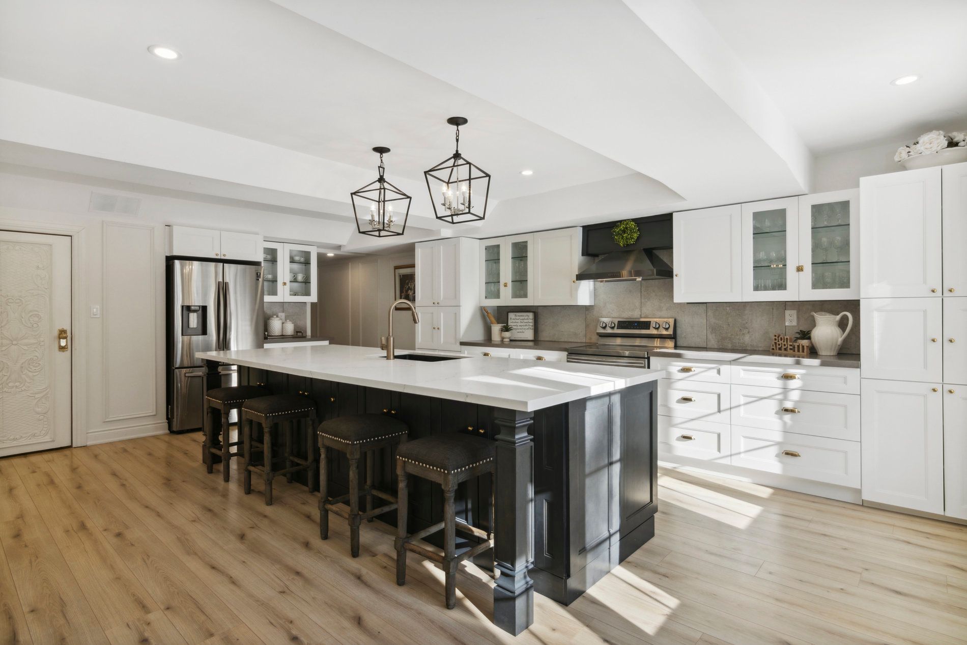 Modern kitchen with black island, white countertops, and white cabinets.