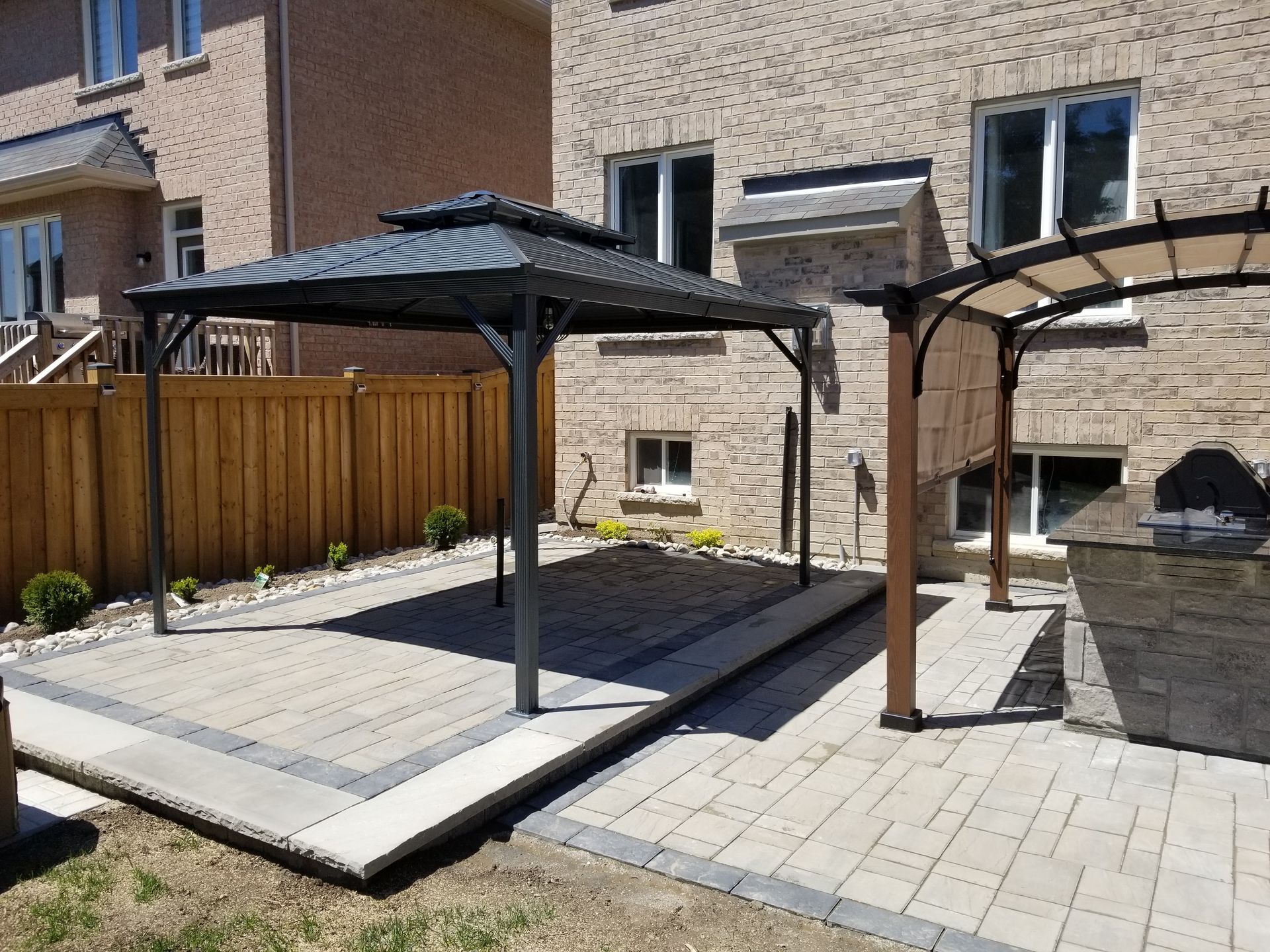 Backyard patio with gazebo and pergola; brick house in background.