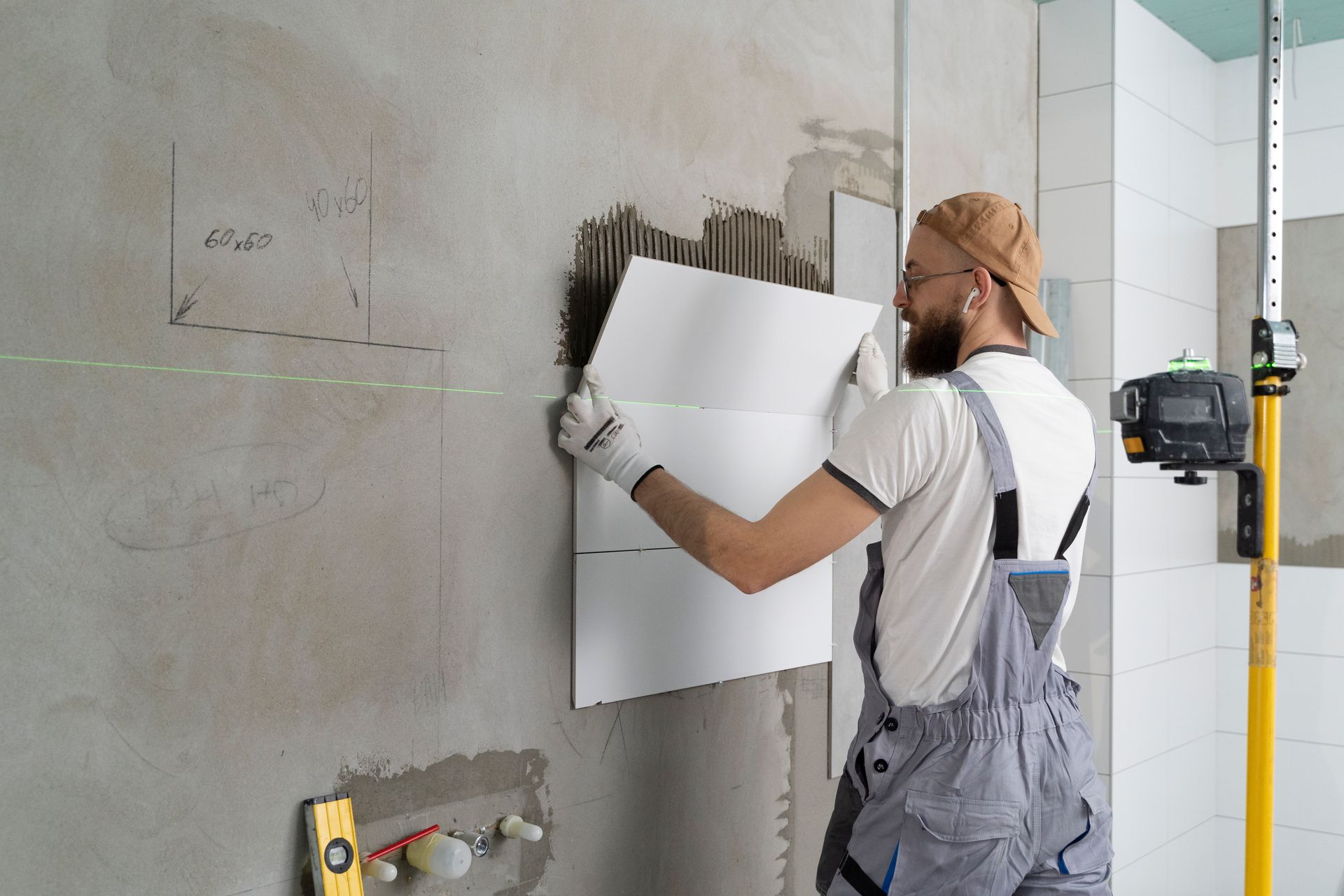 A man is installing tiles on a wall in a bathroom.