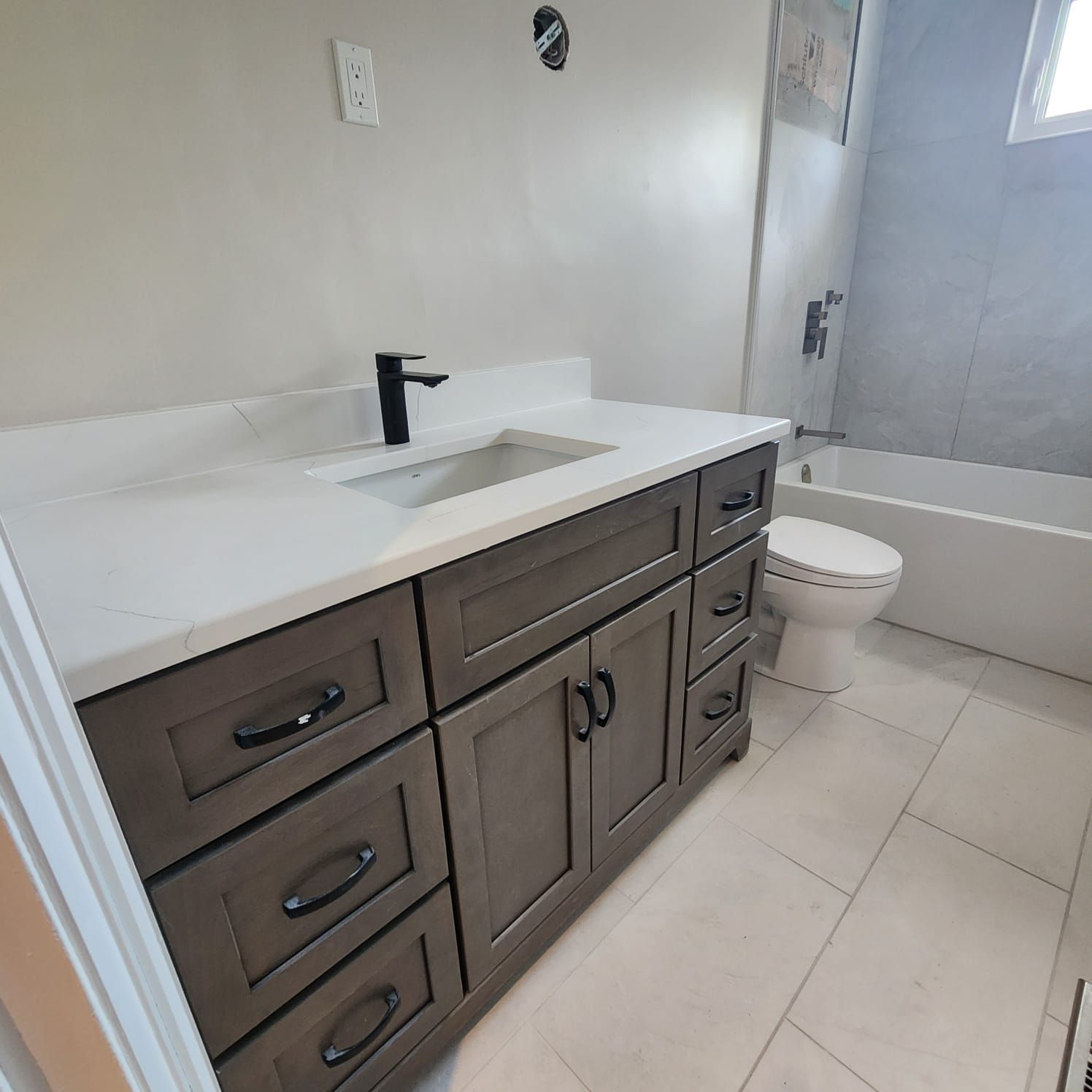 Bathroom with a gray vanity, white countertop, black faucet, and white tile floor.
