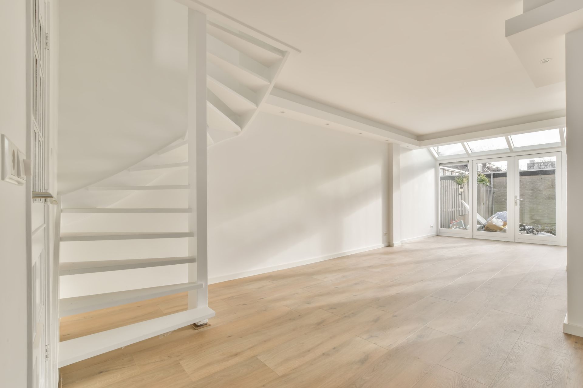 There is a spiral staircase in the middle of a spacious walkout basement.