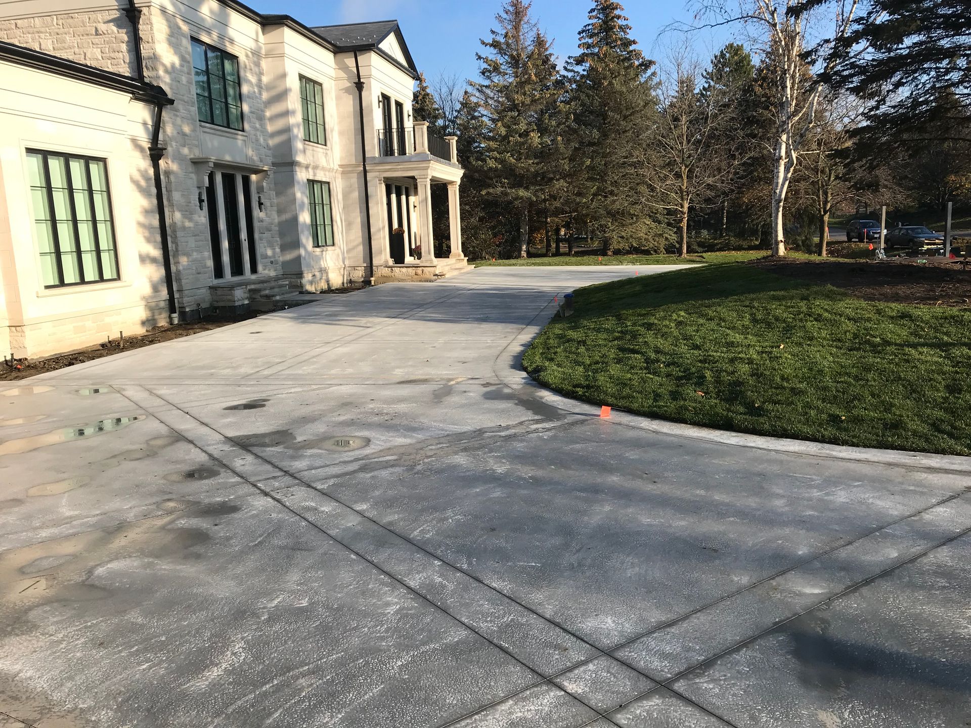 A large white house with a concrete driveway in front of it.