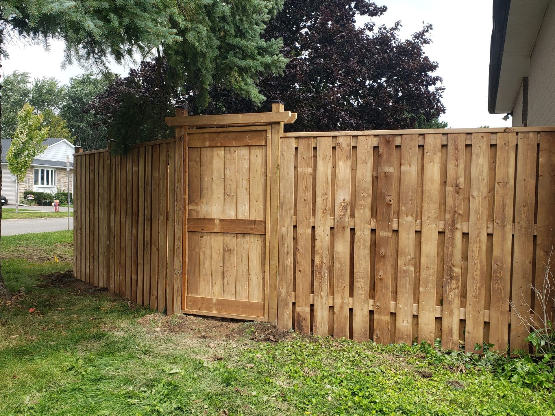 Wooden fence with a gate in a grassy yard.