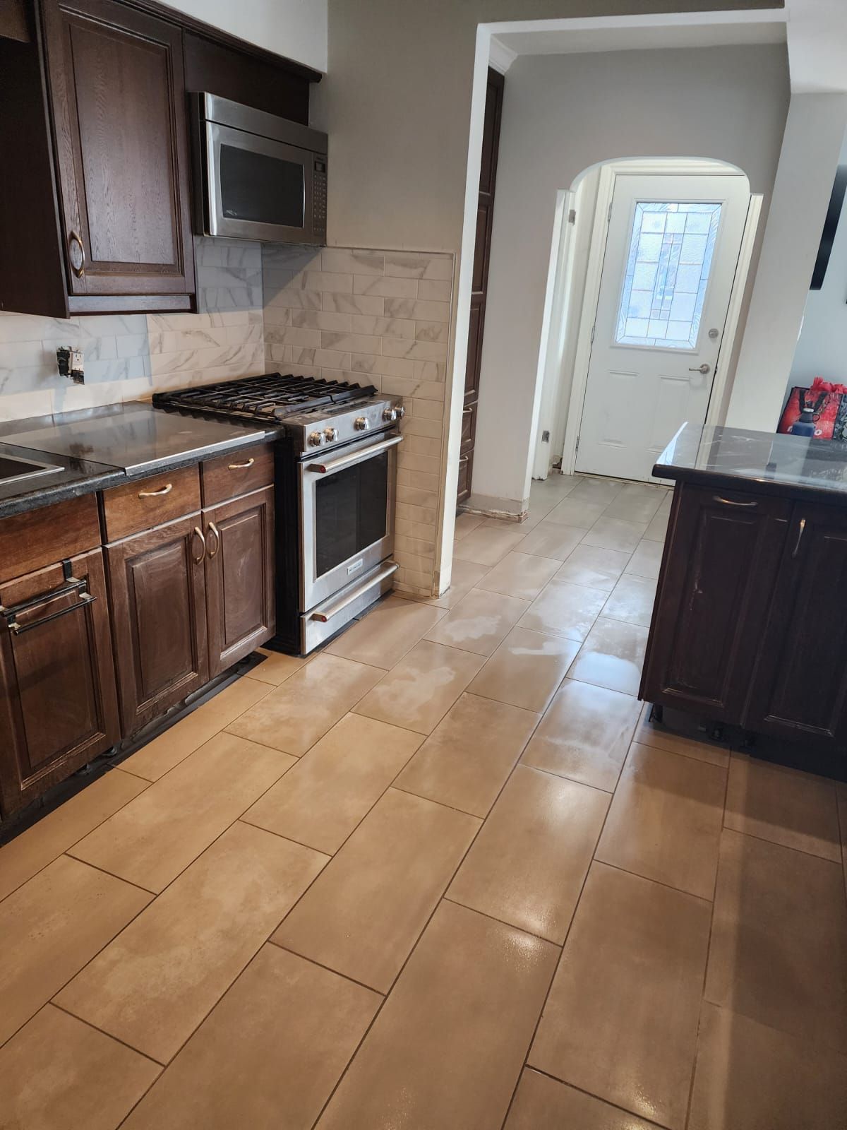 Kitchen with brown cabinets, stainless steel appliances, and beige tile floor.