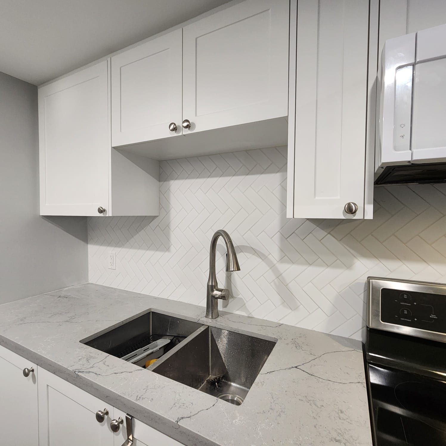 A kitchen with white cabinets and a stainless steel sink