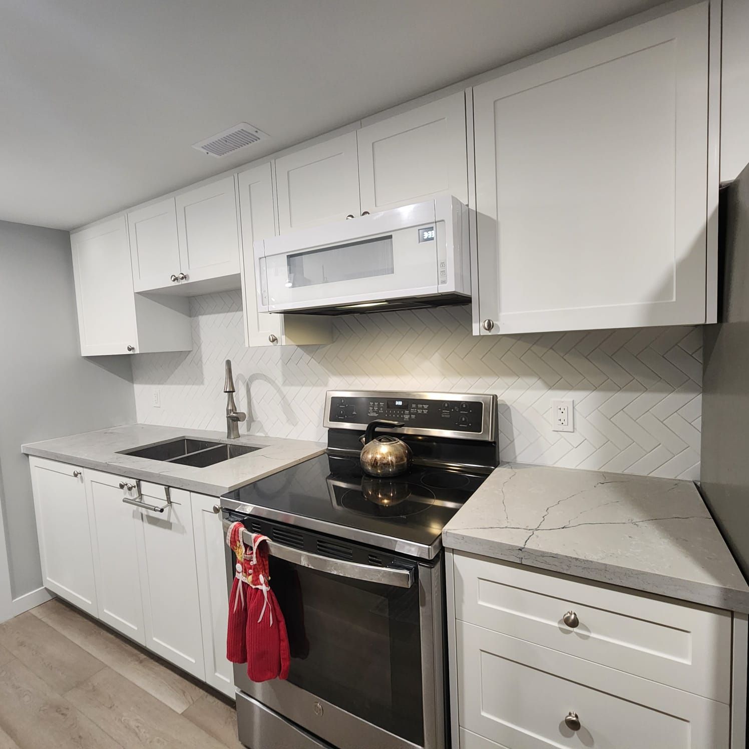 White kitchen with cabinets, stove, microwave, and countertops.