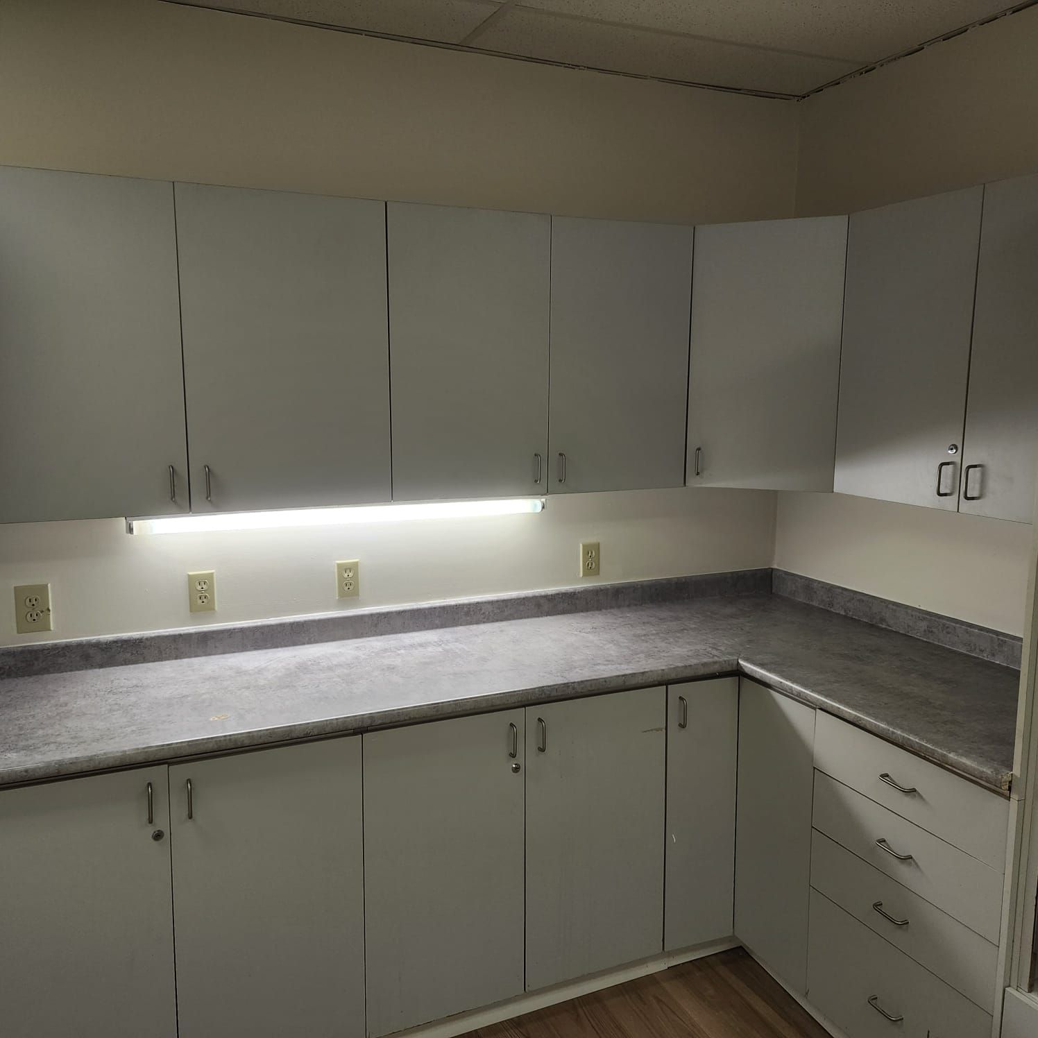 White cabinets with a gray countertop in a corner kitchen setting.