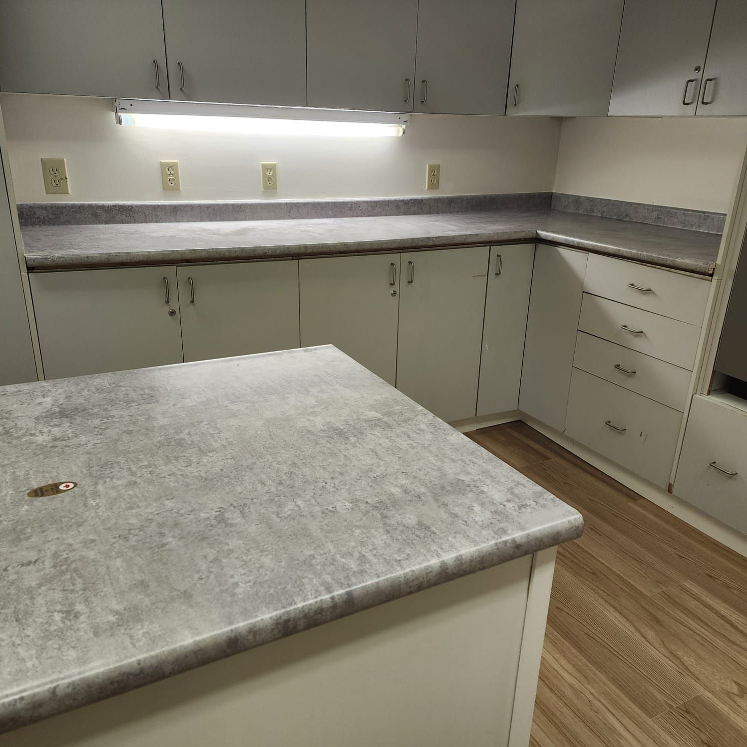 Kitchen with white cabinets, light countertops, and wood-look flooring.