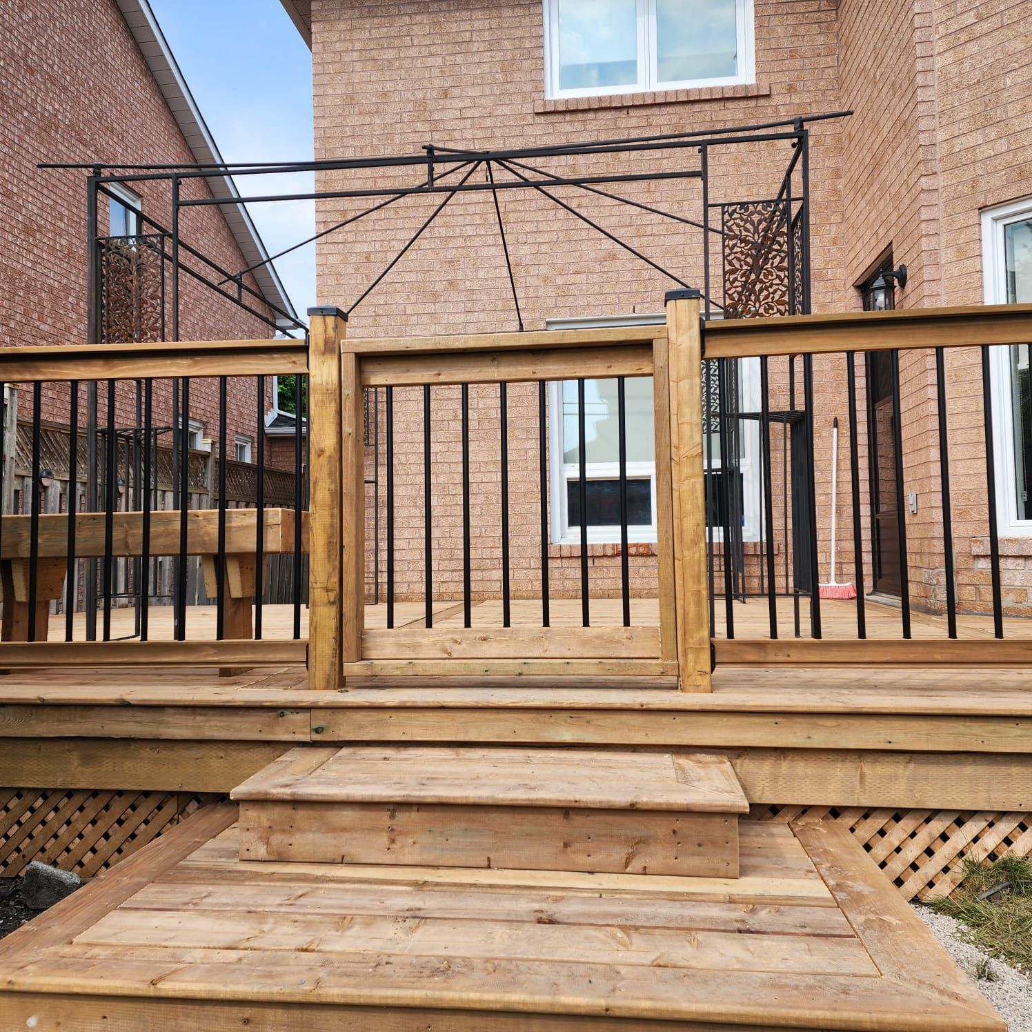 Wooden deck with stairs, railing and gate leading to a backyard with gazebo.