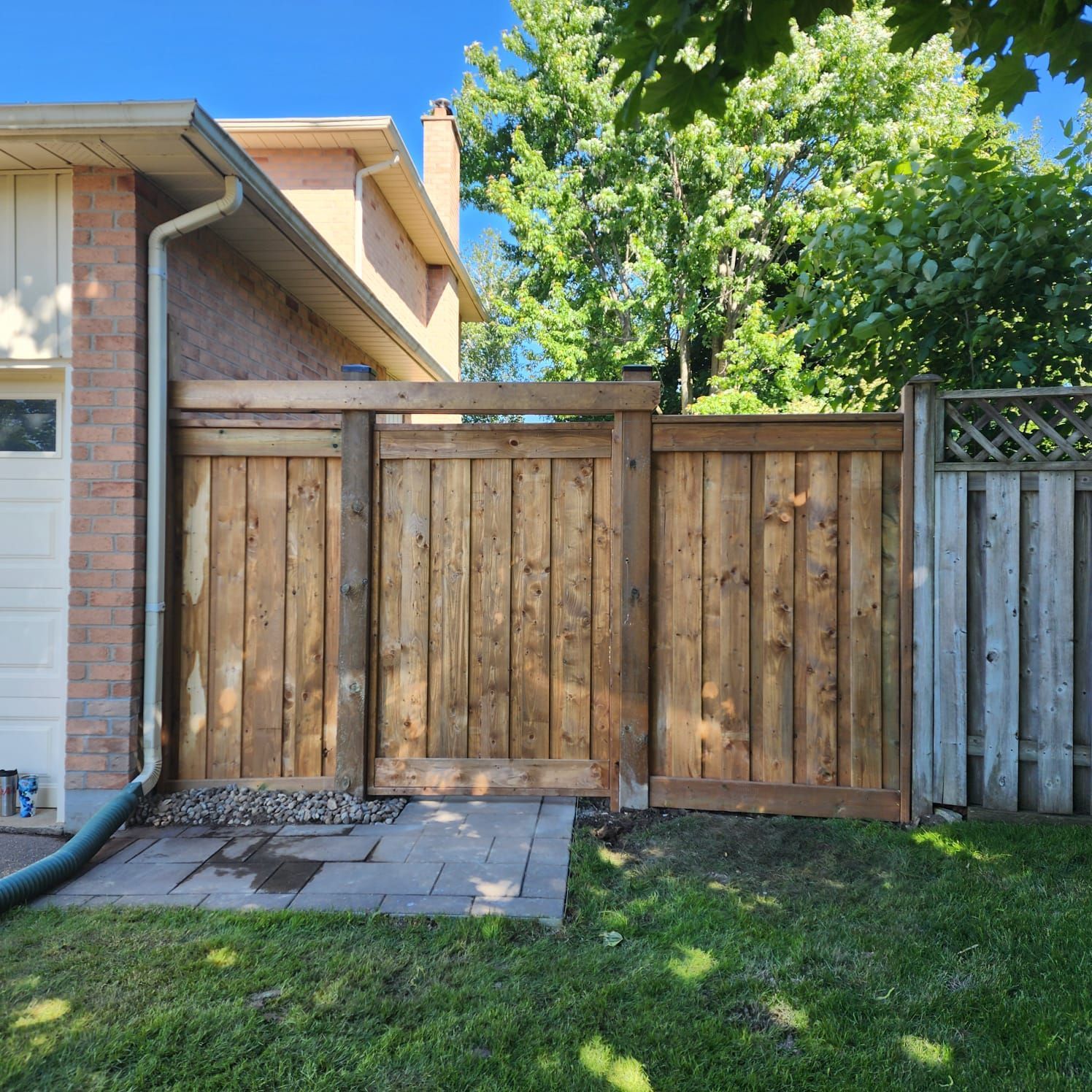 Wooden fence gate with stained planks in a backyard setting.