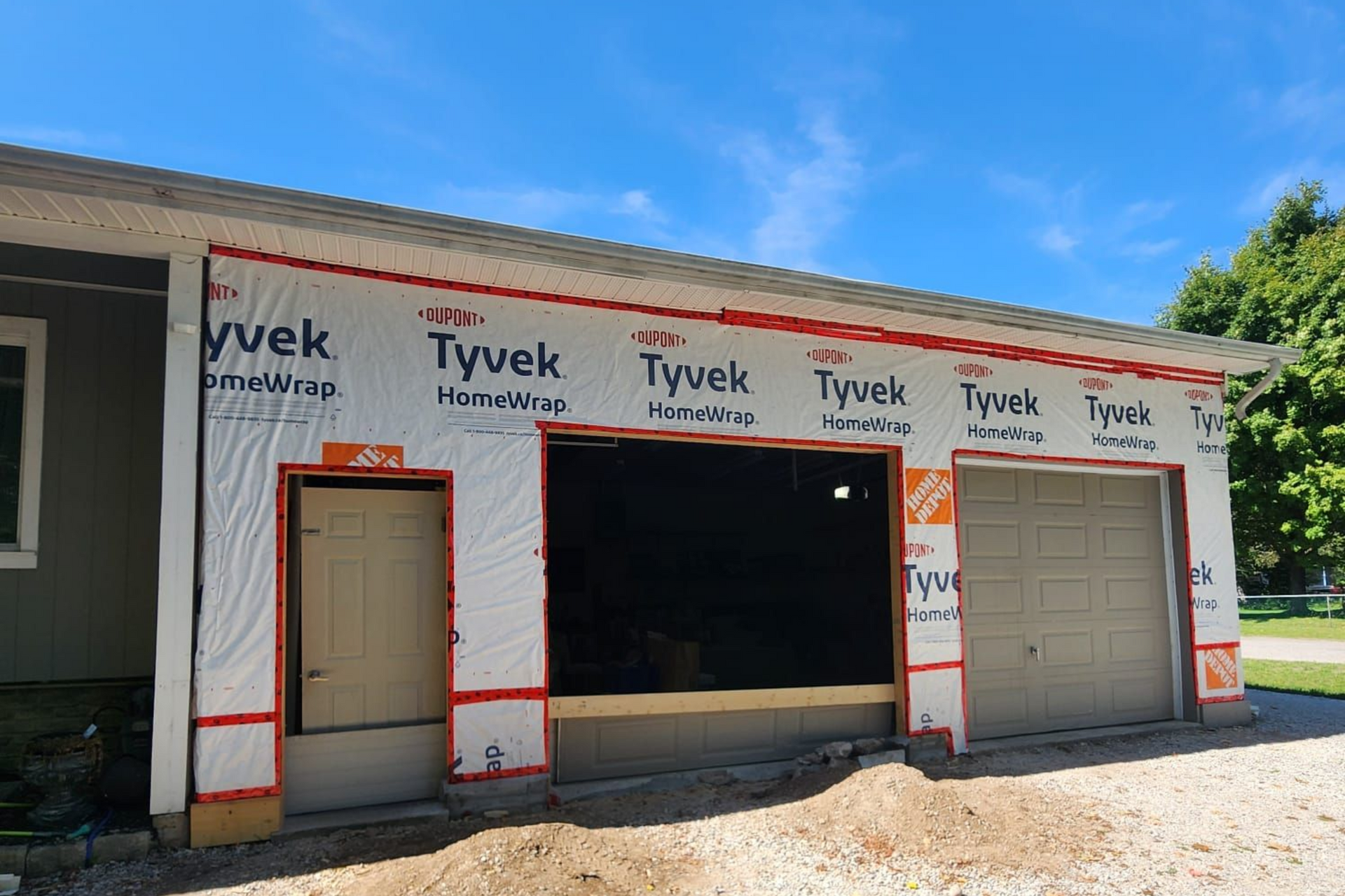 A gray garage door is sitting in front of a gray house.