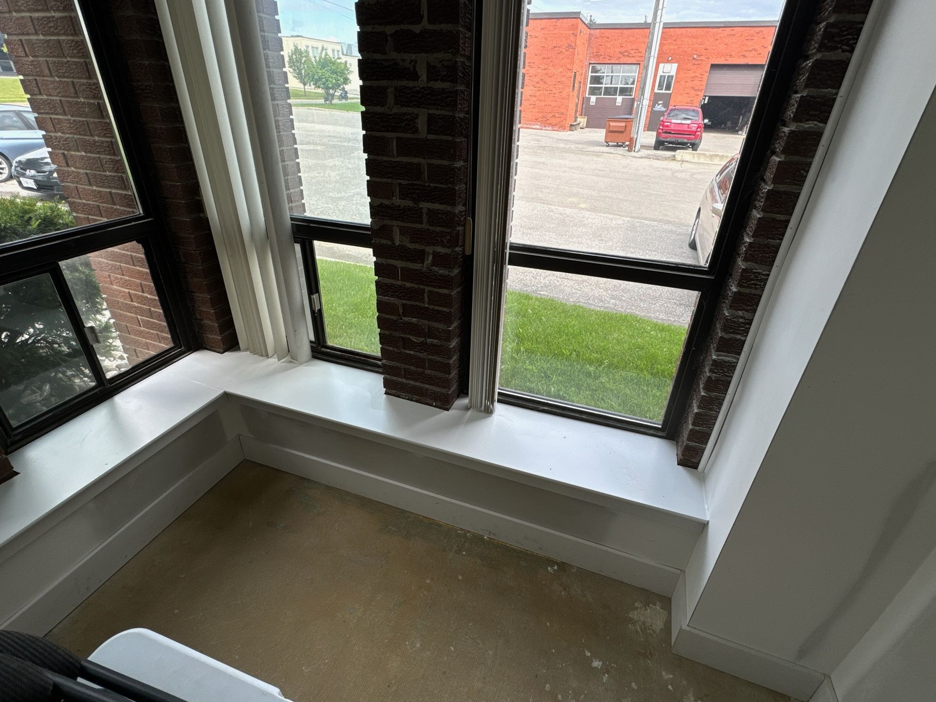 Interior window seat with brick, white trim, and a view of a street and brick building.