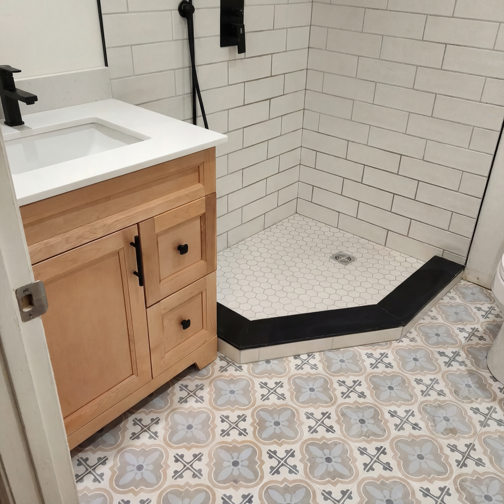 A bathroom with a sink , shower , and tile floor.