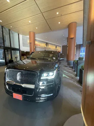 Black Lincoln Navigator SUV parked in a hotel entrance with modern architecture and warm lighting.