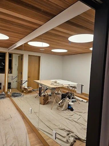Interior construction site with wood ceiling, round lights, a work table, and a door.