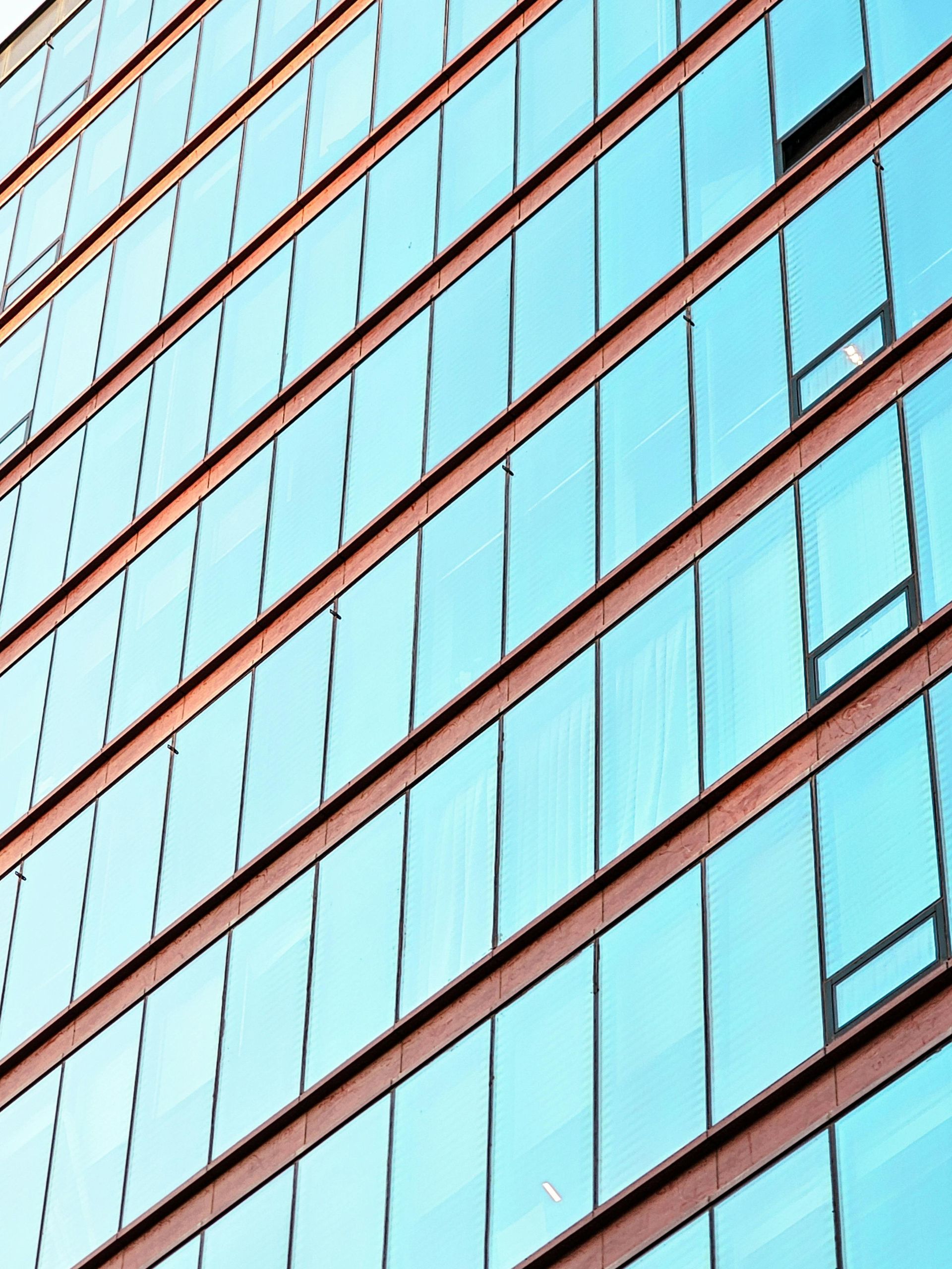 Modern building exterior with many blue windows and brown framing.