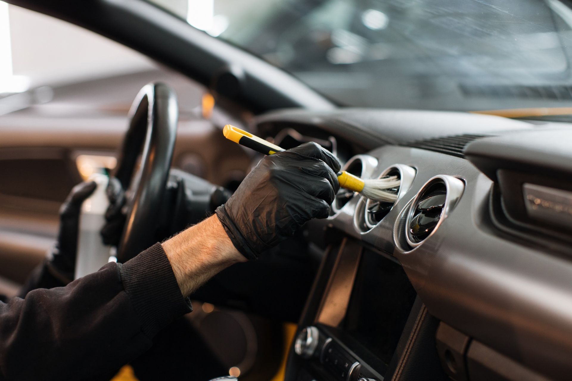 a man is cleaning the dashboard of a car with a brush .