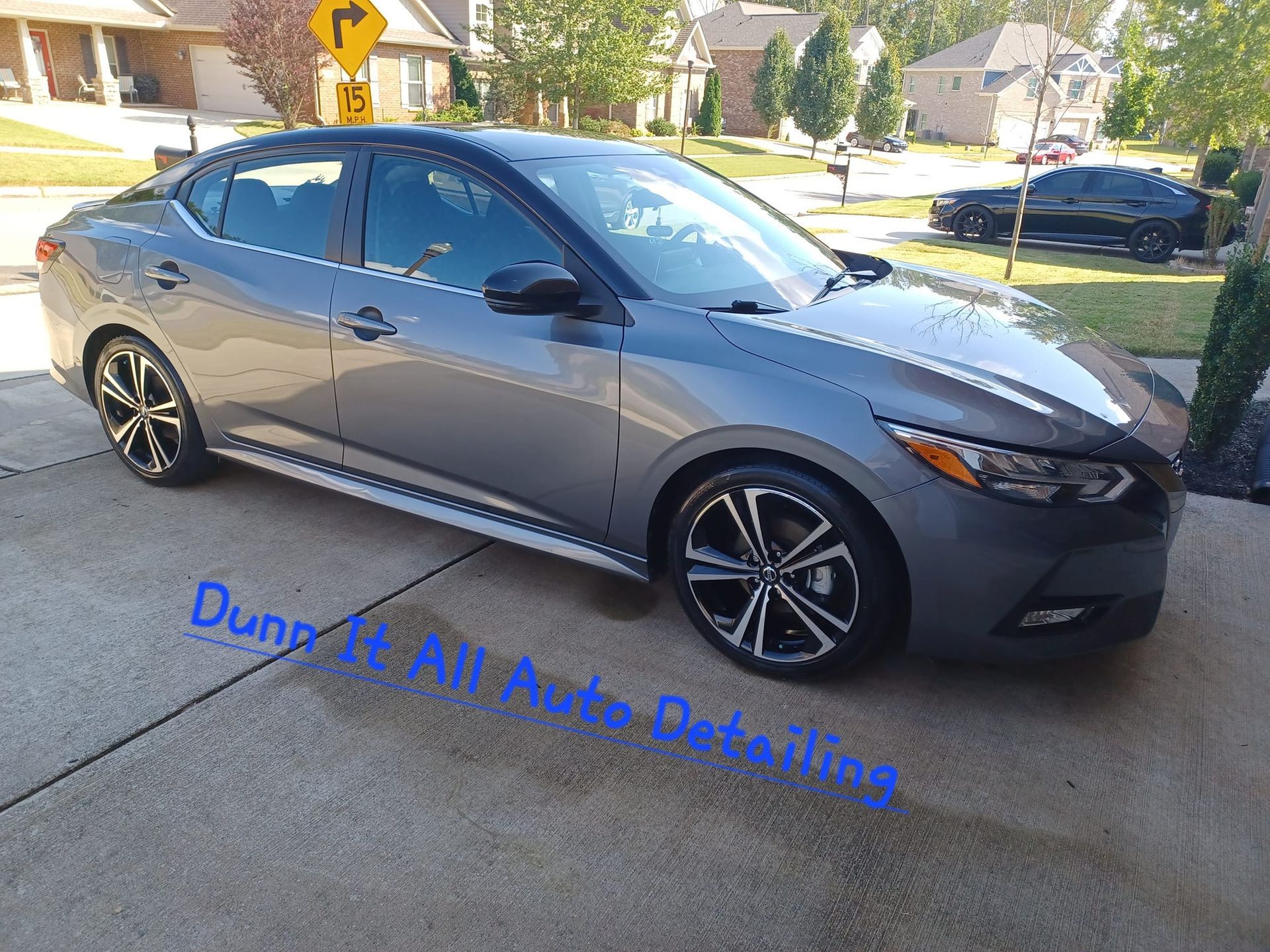 a gray car is parked on the side of the road in front of a house .
