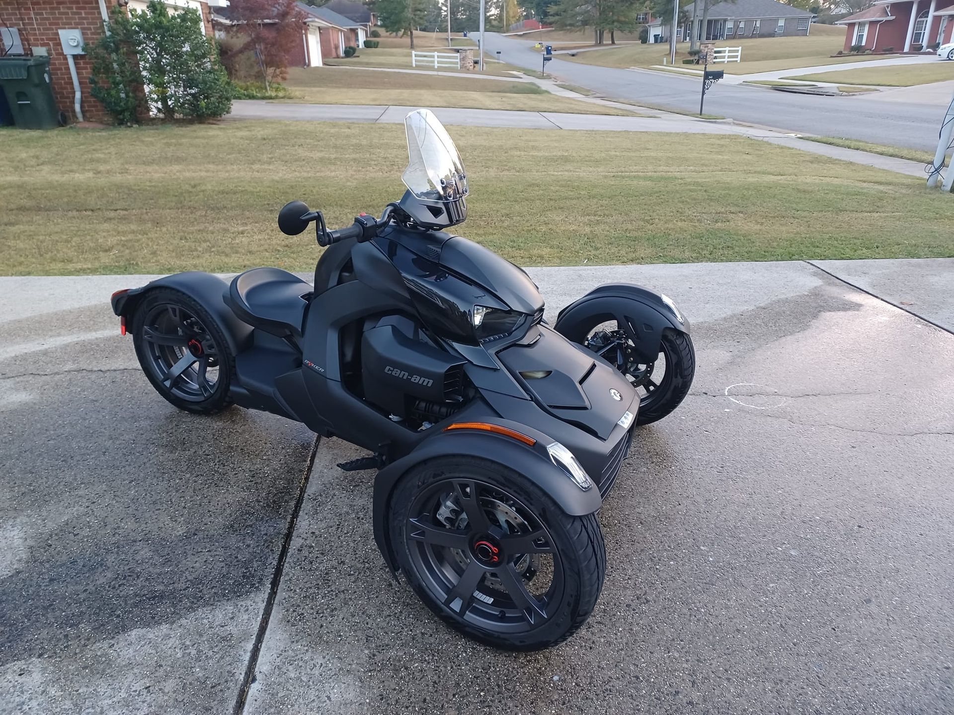 a black motorcycle with three wheels is parked on a sidewalk