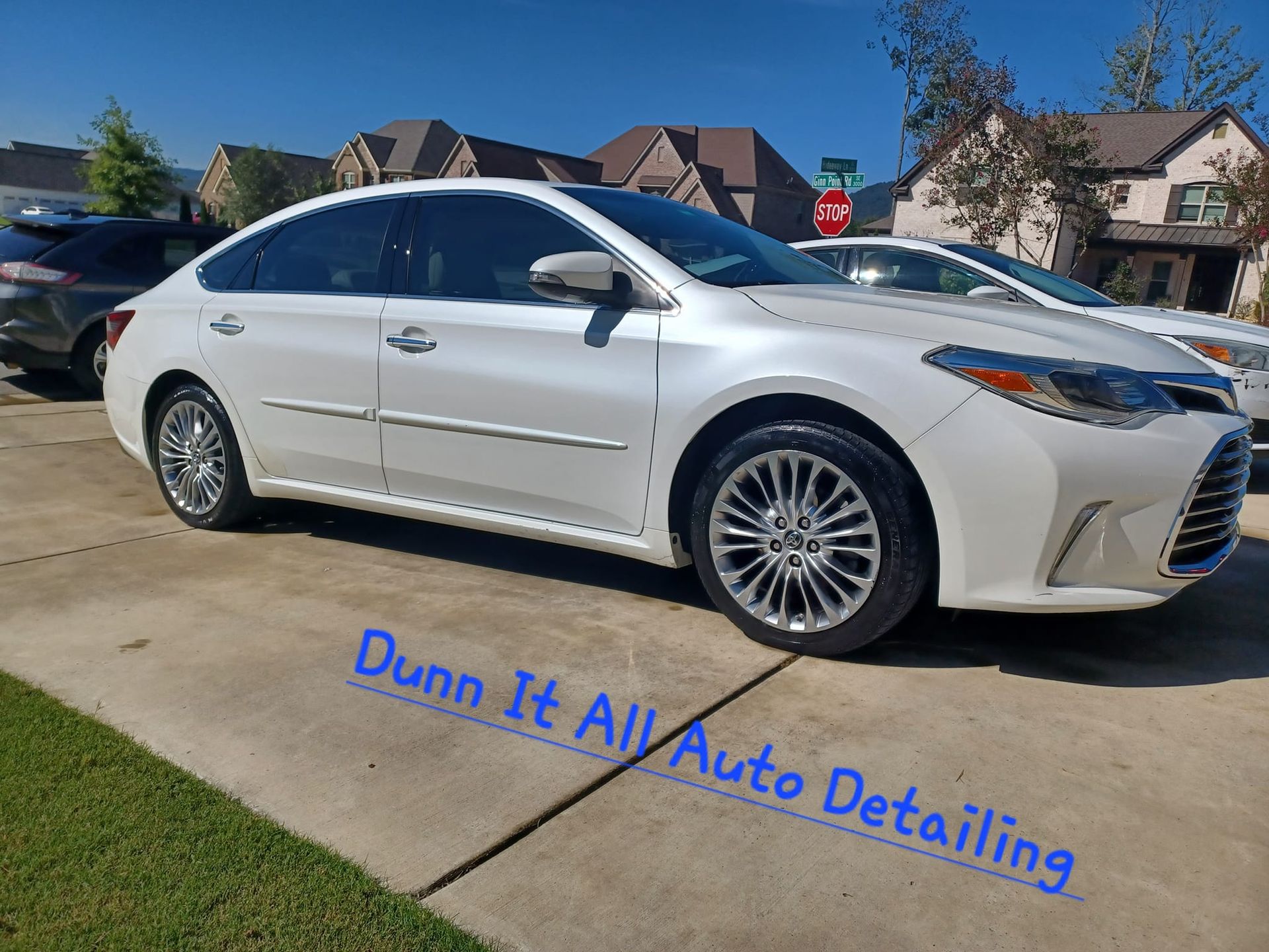 a white car is parked in a driveway next to a stop sign .