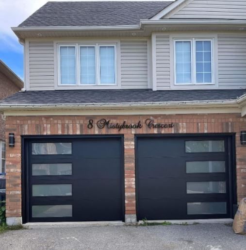 A house with a black garage door that says 8 mainbrook avenue