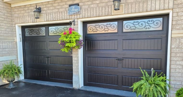 There are two garage doors in front of a brick building.