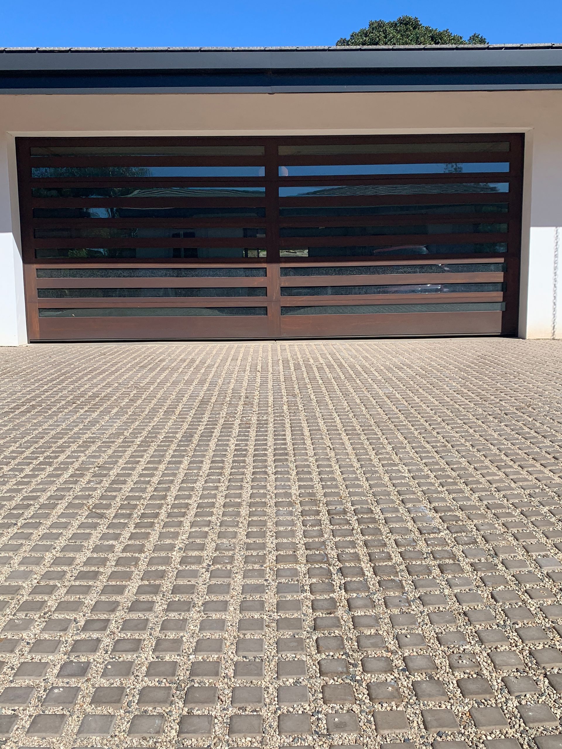 A garage door with a brick driveway in front of it.