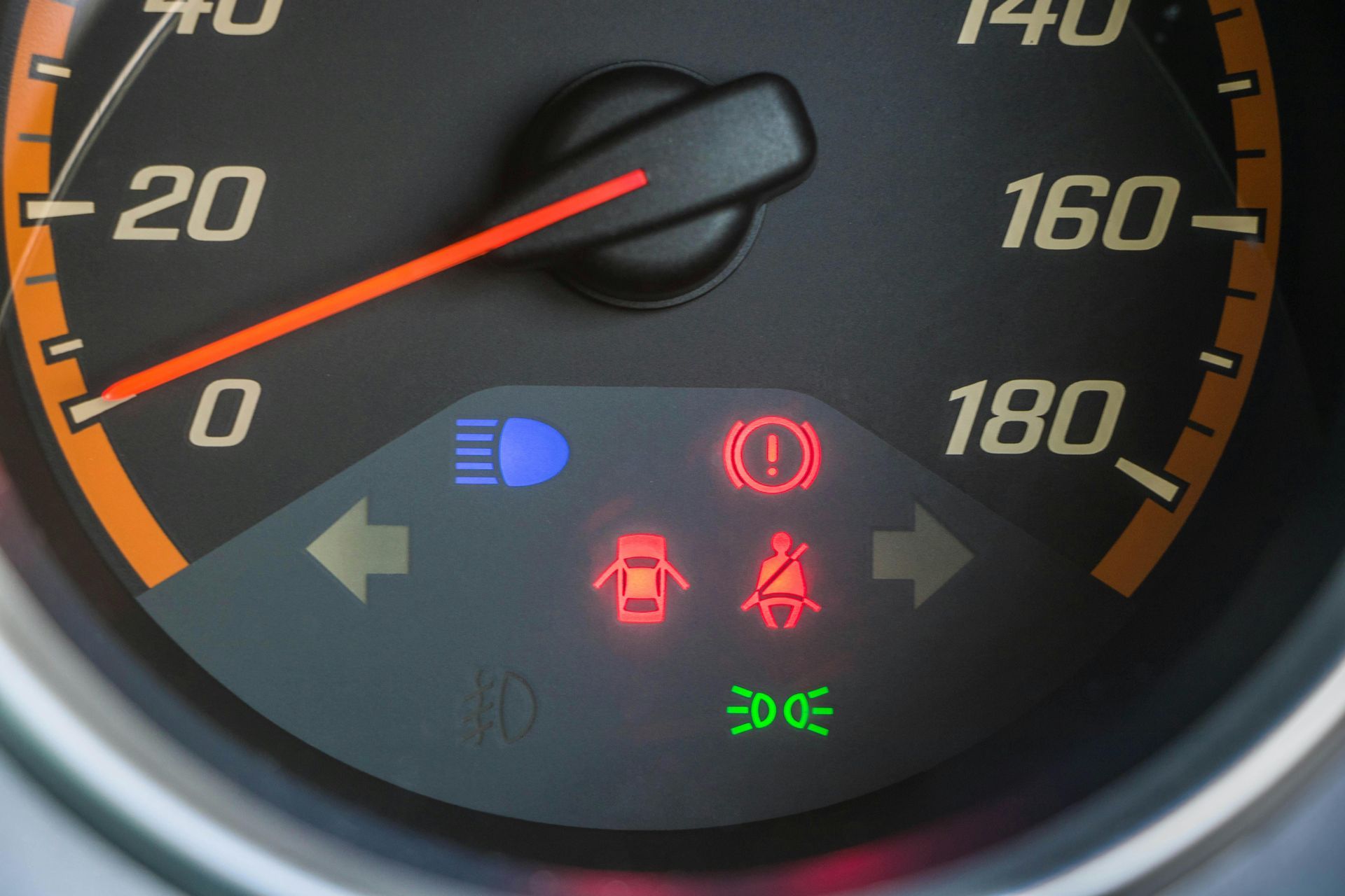 Car dashboard with illuminated warning lights: headlights, brakes, airbags, seatbelt, and lights.