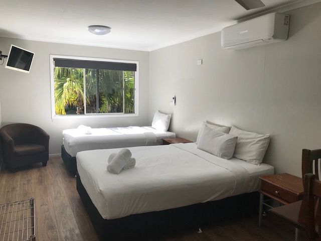 A Hotel Room With Two Beds , A Chair And A Television — Bush Village Holiday Cabins In Cannonvale, QLD