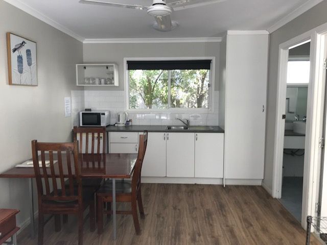 A Kitchen With A Table And Chairs And A Ceiling Fan — Bush Village Holiday Cabins In Cannonvale, QLD