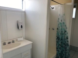 A Bathroom With a Sink, Shower and Window — Bush Village Holiday Cabins In Cannonvale, QLD