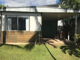 A Mobile Home With a Covered Porch and a Large Window — Bush Village Holiday Cabins In Cannonvale, QLD