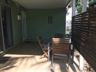 There is a Table and Chairs on the Porch of a House — Bush Village Holiday Cabins In Cannonvale, QLD