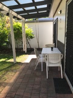 A Patio With A Table And Chairs Under A Pergola — Bush Village Holiday Cabins In Cannonvale, QLD