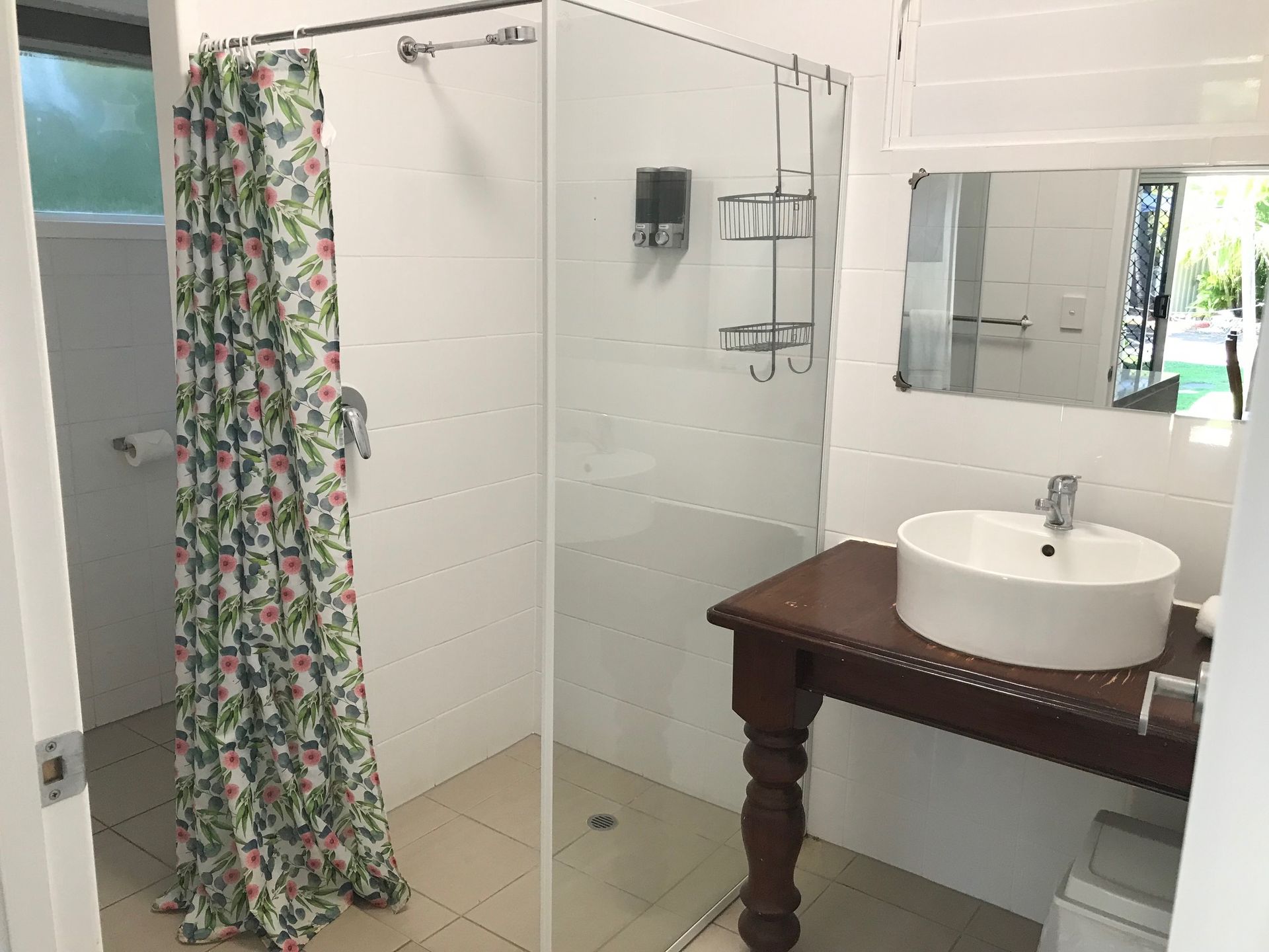 A Bathroom With A Sink, Shower, And Mirror — Bush Village Holiday Cabins In Cannonvale, QLD