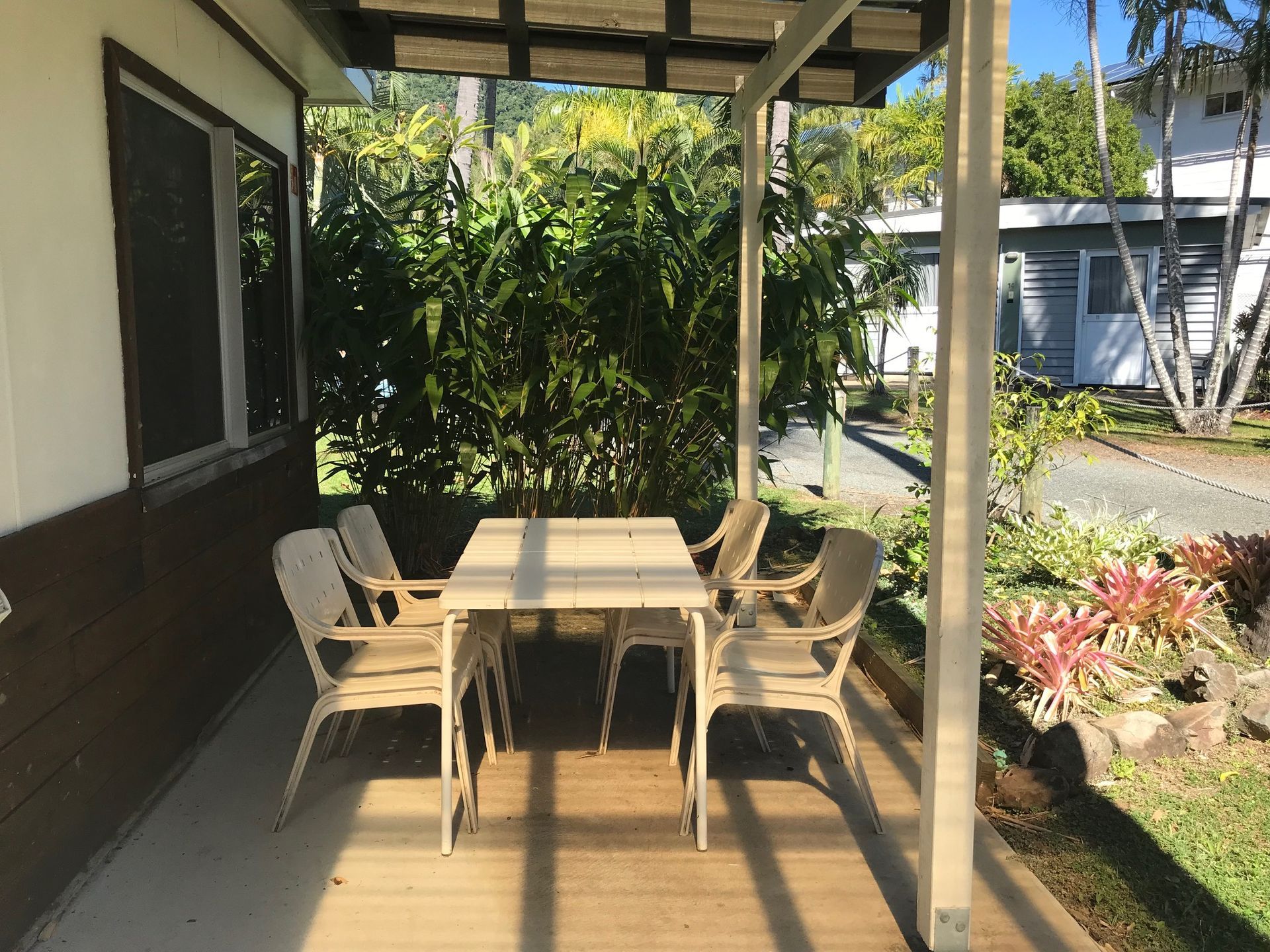 A Patio With A Table And Chairs Under A Pergola — Bush Village Holiday Cabins In Cannonvale, QLD